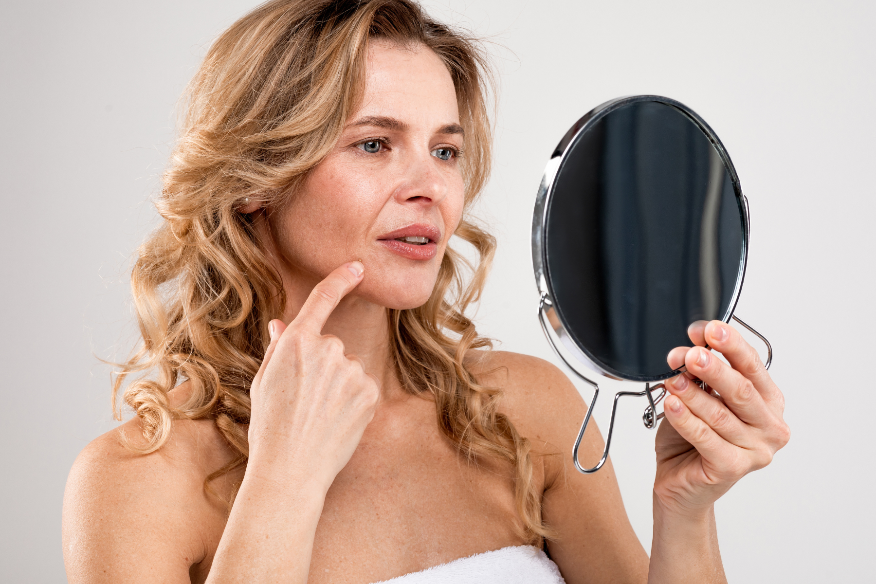 Woman looking into mirror point at face